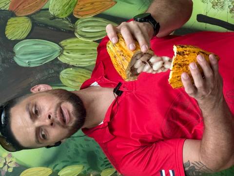       Person in a red shirt holding a split open cocoa pod.
  
