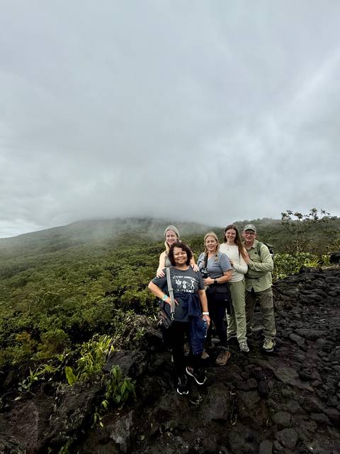       Group of people posing in front of a cloudy mountain landscape.
  