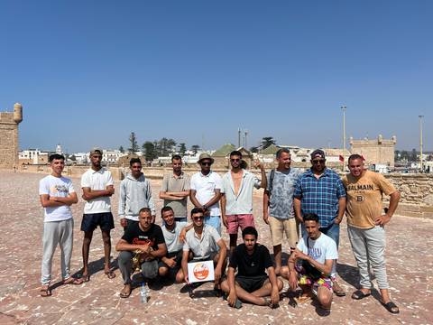 Group of men standing on a stone-paved area with a city view.