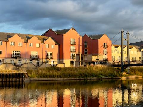 Colorful row of riverside buildings lit by sunlight.