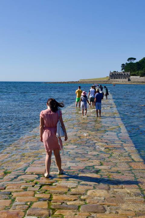 People walking on a causeway leading to an island fort.