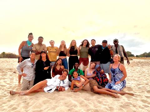 Large group of people posing on a beach.
