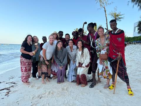 Group of people posing on a beach.