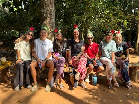People sitting on benches in a forest with flower decorations.