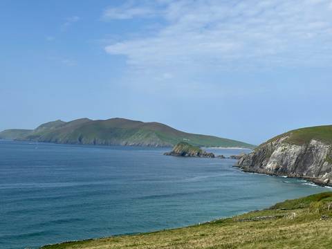 Scenic coastline with rolling green hills meeting the ocean.