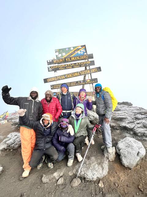 Group at the Uhuru Peak, Mount Kilimanjaro summit sign.