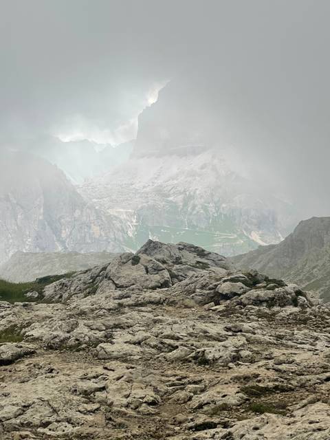       Rocky landscape covered in mist with mountains in the background.
  