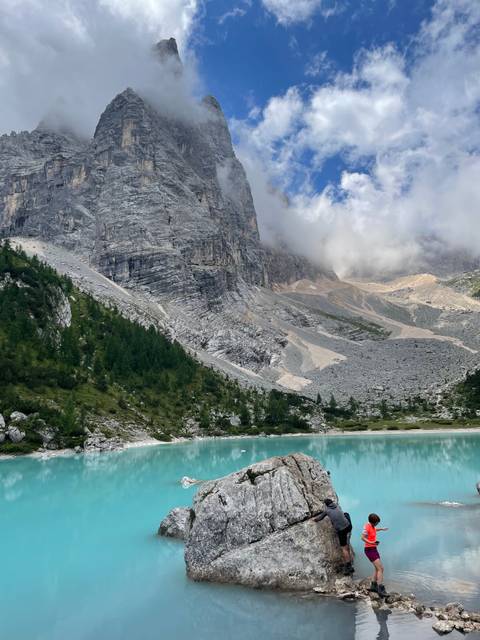 Emerald green lake surrounded by forest and rocky mountains.