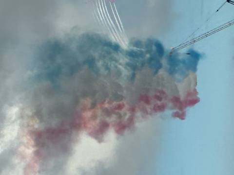 Colorful smoke trails from aircraft in a blue sky.
