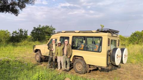 Tourists posing with a safari jeep.
