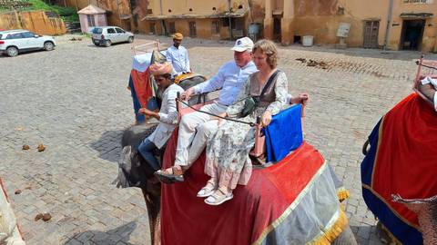 Couple riding an elephant with a guide.