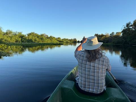       Man sitting in a boat on a calm river.
  