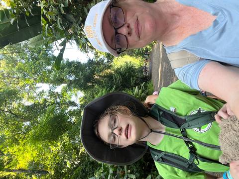 Two people posing with backpacks in a lush green forest trail.