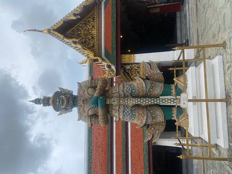 Giant statue at a temple with ornate architecture.