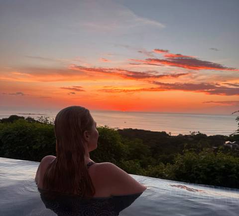 Person enjoying a sunset view over the ocean from an elevated position.