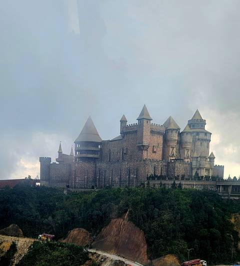 Castle-like structure with turrets against a cloudy sky.