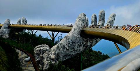       Iconic bridge held up by giant hands in a mountain setting.
  