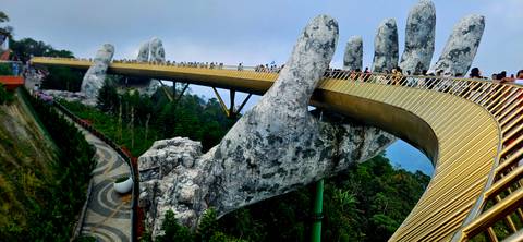 Golden Bridge with stone hand structures in a misty mountain environment.