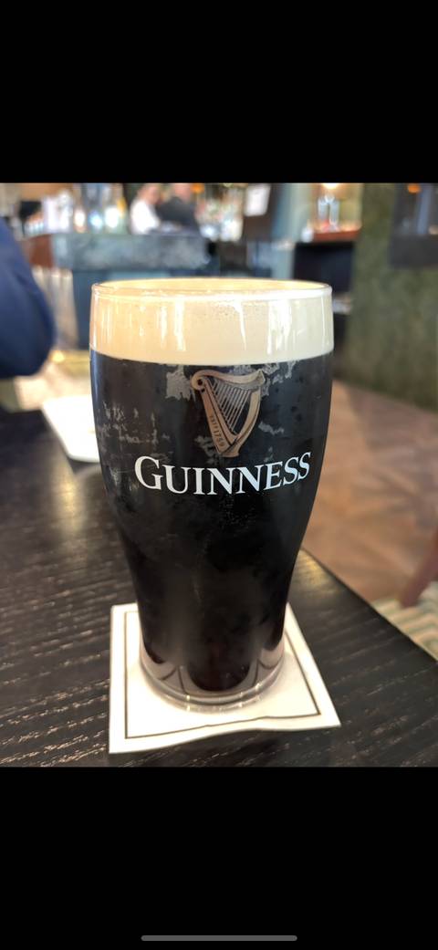       Pint of Guinness beer with a foamy top on a table.
  