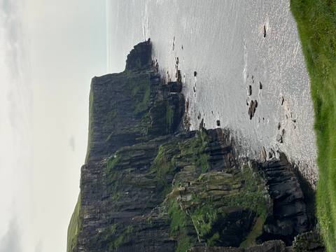       Towering cliffs over a vast ocean under a cloudy sky.
  
