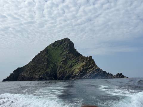       Isolated island with steep rocky cliffs seen from the sea.
  