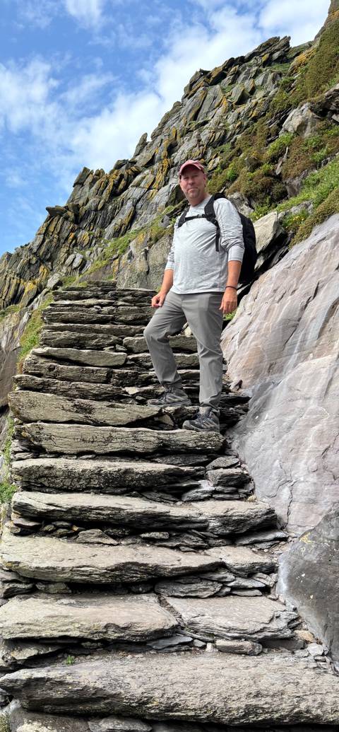       Person standing on a rocky staircase with boots.
  