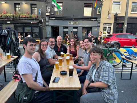       Group of people enjoying drinks outside a pub.
  