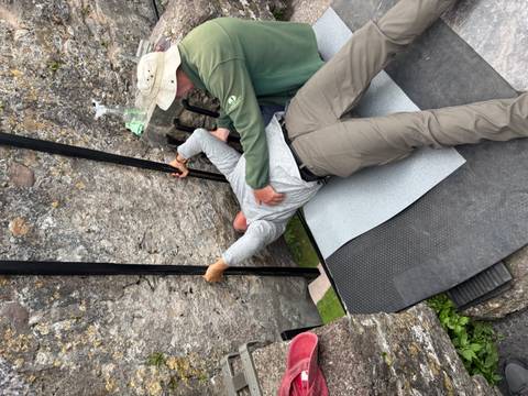       Person kissing the Blarney Stone with assistance.
  