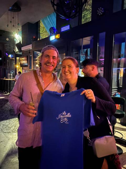 Two people indoors, one holding a t-shirt.