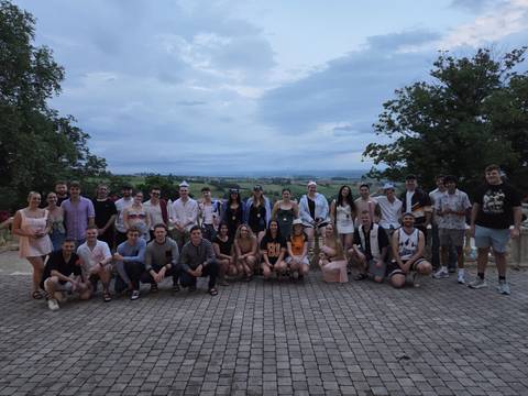 Large group posing outdoors with a scenic view.
