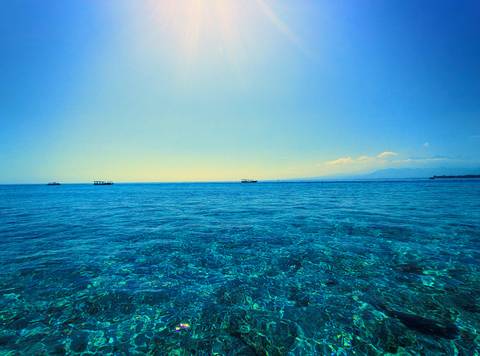 Vast ocean with clear blue waters and distant boats.