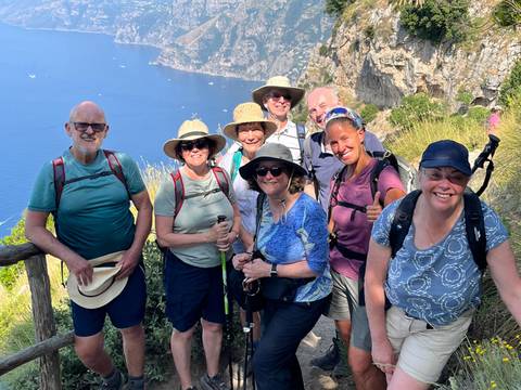 Group of hikers posing with a seaside view in the background.