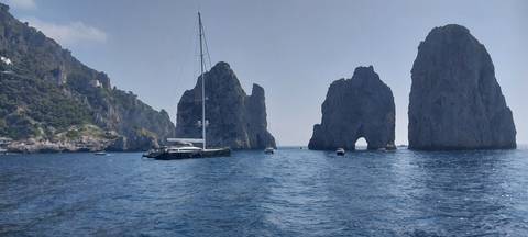       Boats in the sea with dramatic rock formations.
  