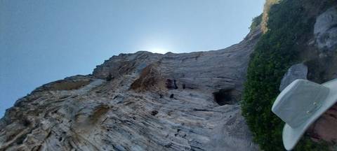       Close-up of a rocky cliff with the sun peeking around it.
  