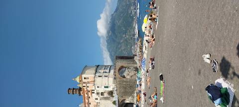      Beach with umbrellas and people, a coastal town in the background.
  