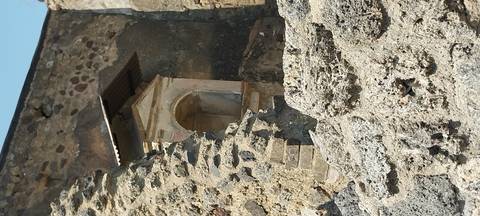       Ruins of ancient architecture with stone walls and a niche.
  