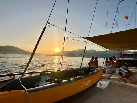 Sailboat at sunset with people relaxing on deck.