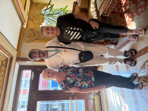 Three people posing inside a decorated room.