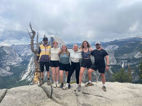       Group of hikers posing with a mountainous landscape in the background.
  