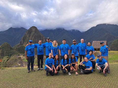 Group of tourists posing in front of Machu Picchu with mountains.