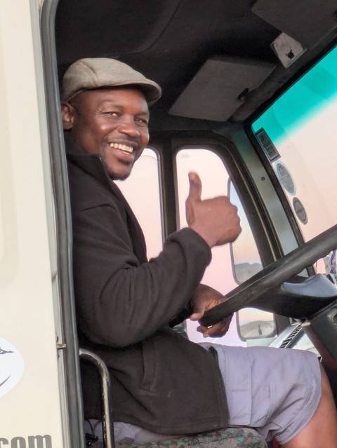 Person inside a vehicle giving a thumbs up.