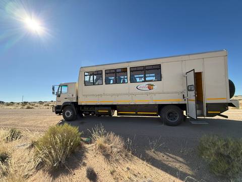 Large safari truck parked in a desert environment.