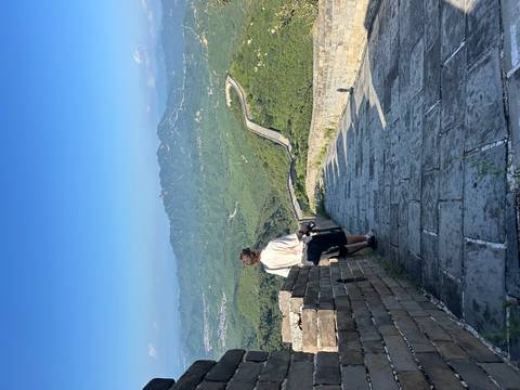 Person standing on the Great Wall of China with a scenic mountain view.