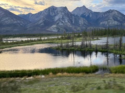 Scenic wetlands with mountains in the background, reflecting on water.