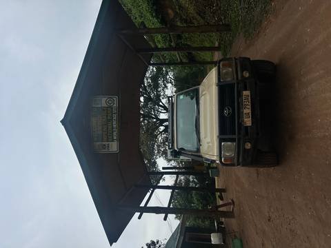       Entrance gate to Bwindi Impenetrable National Park with a vehicle parked.
  