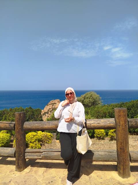       Person standing by the sea with nature around.
  
