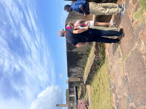People exploring historic stone ruins under a bright blue sky.