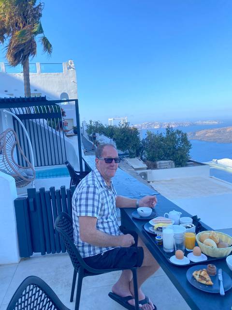       A man sitting at a cafe with a scenic ocean view.
  