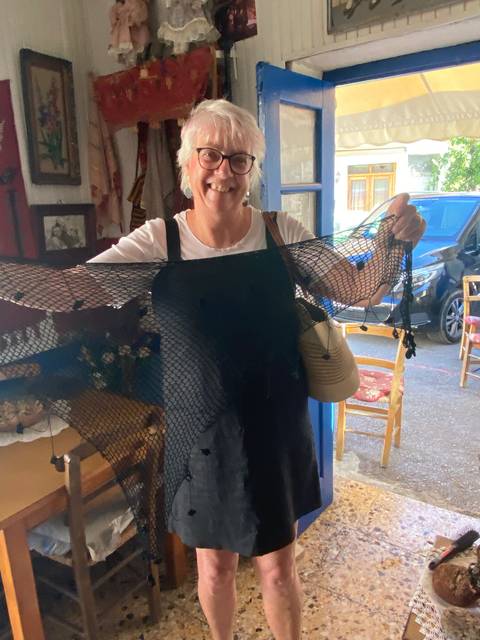 A woman displaying a net-like craft in a local store.
