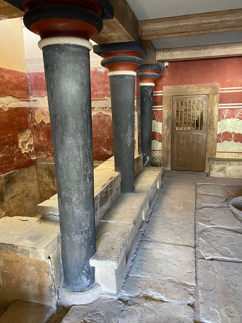 Interior of an ancient structure with columns and frescoes.